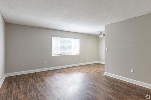 an empty living room with hardwood floors and a large window at Summit Augusta, Augusta Georgia