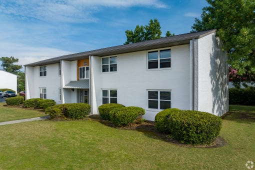 a white apartment building with a green lawn and bushes in front of it at Summit Augusta, Augusta