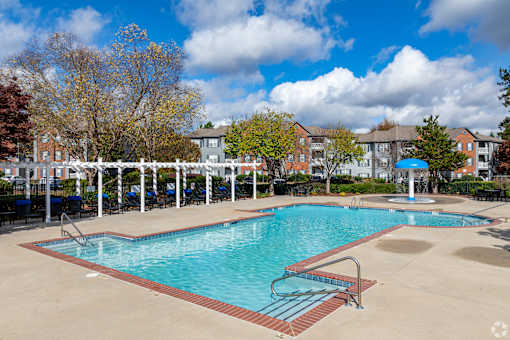 A large swimming pool surrounded by a white fence and trees.
