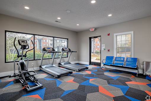 A gym with treadmills, elliptical machines, and a bench.