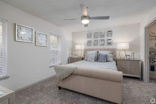A bedroom with a bed, nightstands, and pictures on the wall.