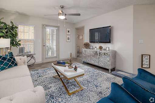 A living room with a white couch, a blue couch, a coffee table, and a television.
