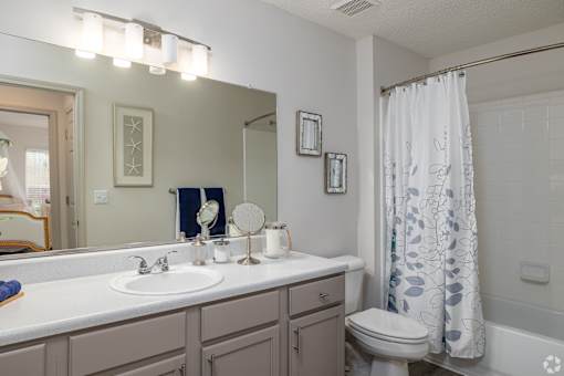 A bathroom with a white sink, toilet, and a shower curtain.