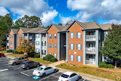 A parking lot in front of a brick apartment building.