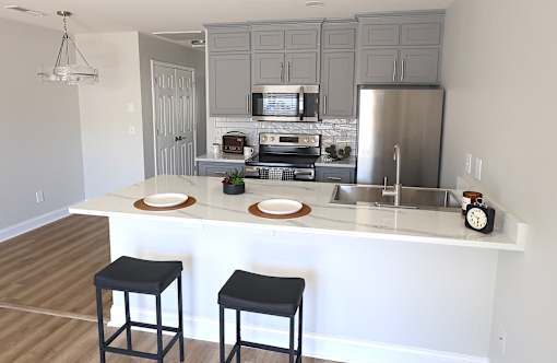 A kitchen with a white island and black stools.
