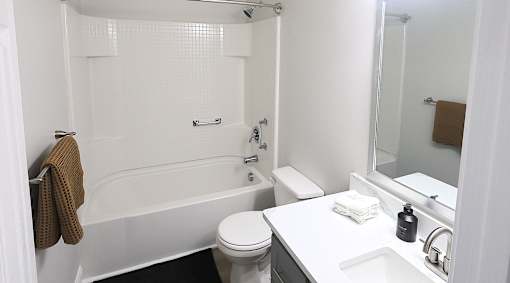 A white bathroom with a toilet, sink, and tub.