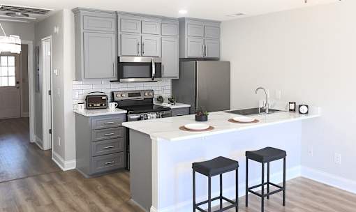A kitchen with a white island and black stools.