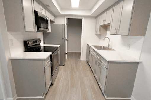 A kitchen with a refrigerator, oven, microwave, sink and cabinets.