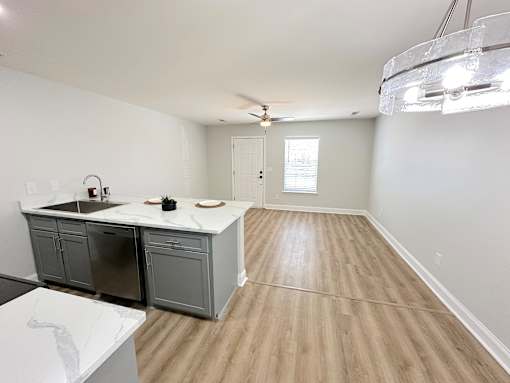 A kitchen with a white countertop and wooden flooring.