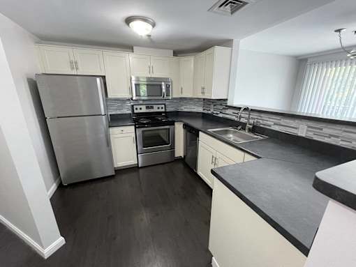 A kitchen with a stainless steel refrigerator, microwave, oven, and sink.
