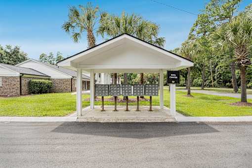 A bus stop with a shelter and benches is located in a grassy area.