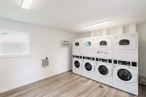 A row of white front load washing machines in a laundry room.