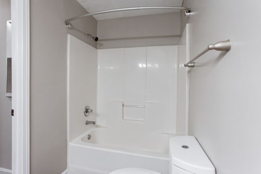 a white bathroom with a white toilet and a bath tub