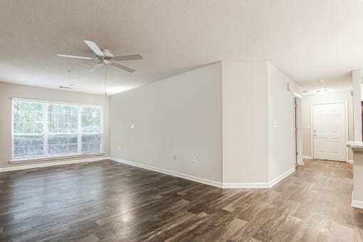 an empty living room with a ceiling fan and a window