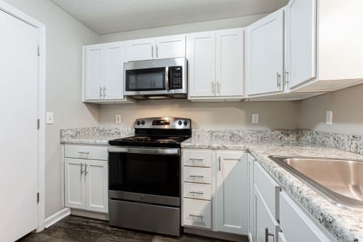 a kitchen with white cabinets and a stove and microwave