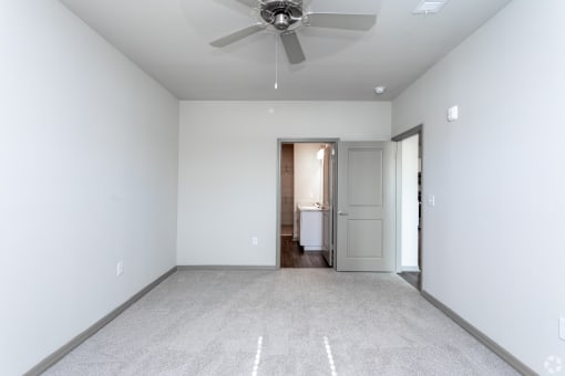 a bedroom with white walls and a ceiling fan