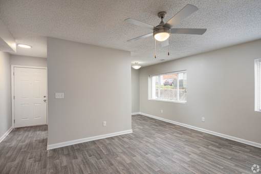 A room with a ceiling fan and a window with blinds.