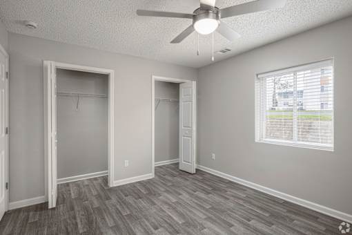 A room with a ceiling fan and a window with blinds.