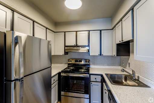 A kitchen with a stainless steel refrigerator and black stove top oven.