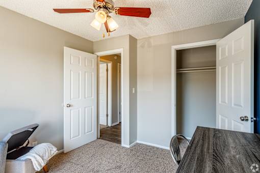 A room with a ceiling fan and a dining table.