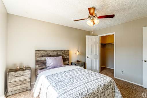 A bedroom with a bed, nightstand, and a ceiling fan.