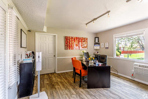 A kitchen with a refrigerator, a chair, a table, and a window.