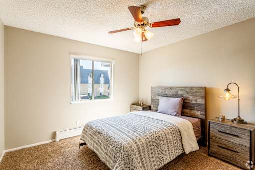 A bedroom with a bed, nightstand, and window.