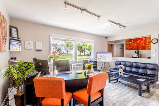 A room with a desk, chairs, and a couch.