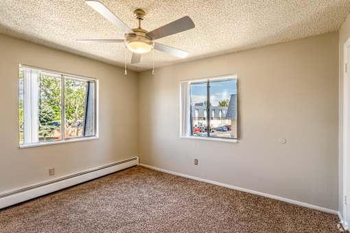 A room with a ceiling fan and two windows.