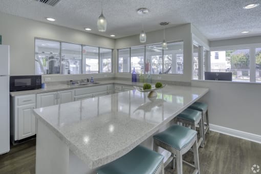 a kitchen with a large island with stools in front of a row of windows at Beach Club, Tampa, 33614