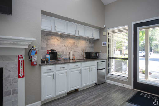 a kitchen with white cabinets and a sink and a window