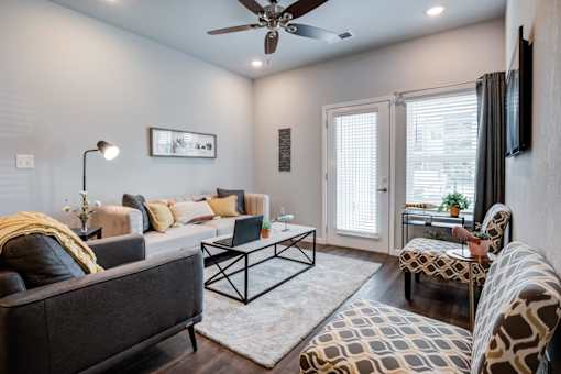 A living room with a grey couch, a coffee table, and a television.