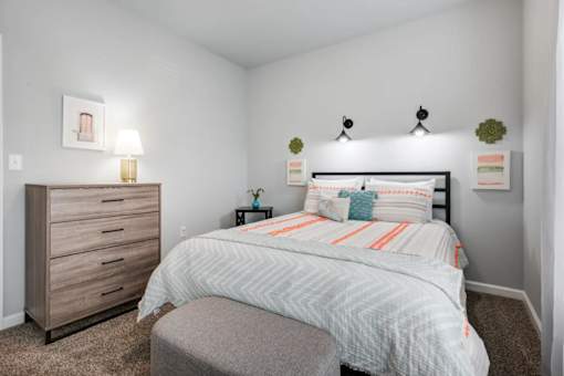 A bedroom with a bed, nightstand, and a dresser.