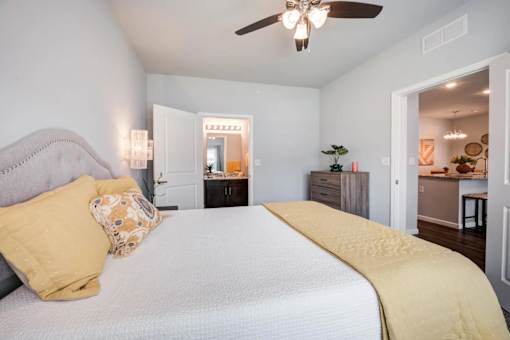 A bedroom with a bed, dresser, and ceiling fan.