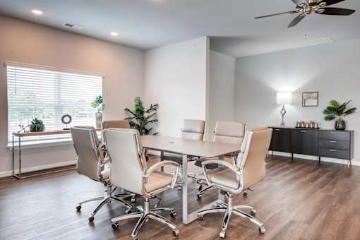 A conference room with a table, chairs, and a ceiling fan.