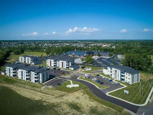 A large apartment complex with a parking lot in front.