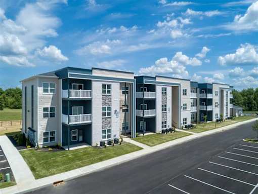 A row of modern apartment buildings with a parking lot in front.