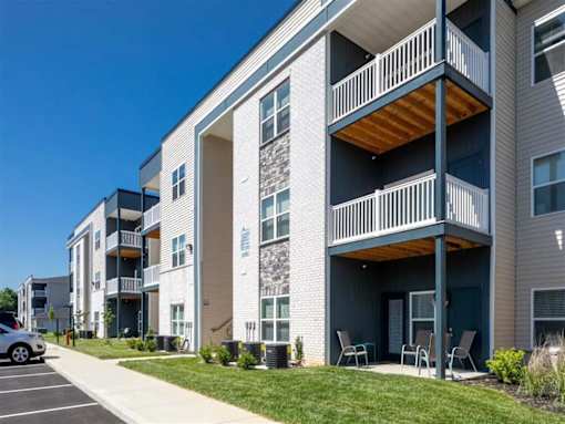 A modern apartment building with a parking lot in front.