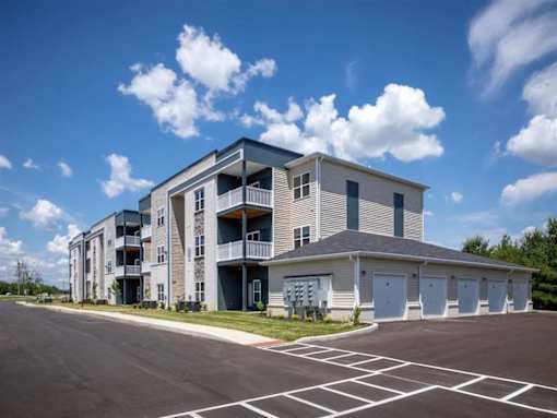 A modern apartment building with a parking lot in front.