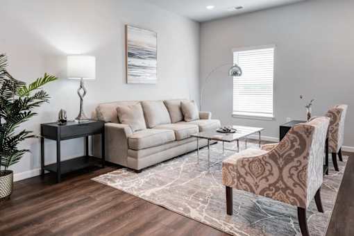 A living room with a couch, chair, and a table with a lamp on it.