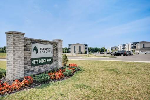 A sign for Garden Estates at 4176 Todds Road stands in front of a building.