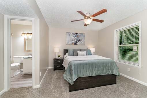 A bedroom with a bed, nightstands, and a ceiling fan.