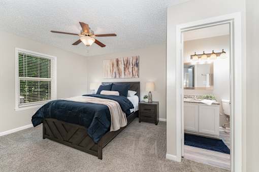A bedroom with a bed, nightstand, and a ceiling fan.