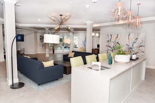 A modern living room with a dark blue sofa and a white kitchen island.