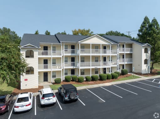 an apartment building with cars parked in a parking lot