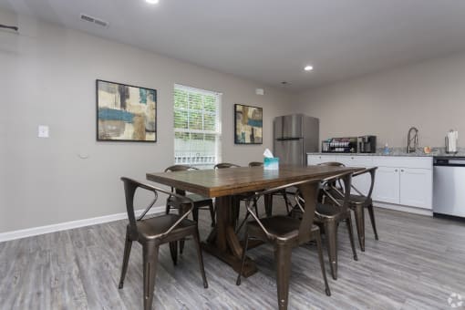 a dining area with a table and chairs and a kitchen with a refrigerator and sink