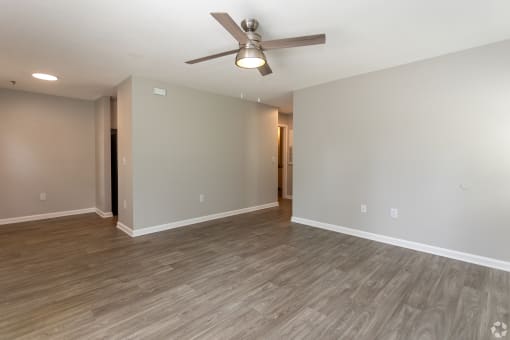 an empty living room with a ceiling fan and wood floors