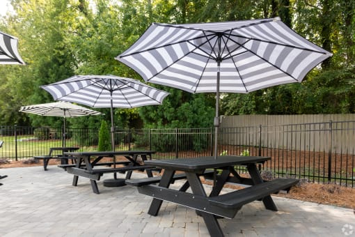 three picnic tables with umbrellas in a park