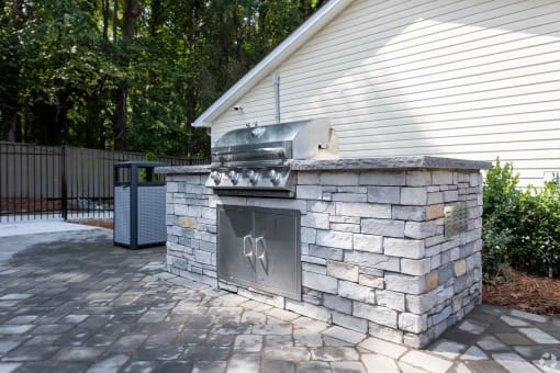 a stone outdoor kitchen with a grill on a patio