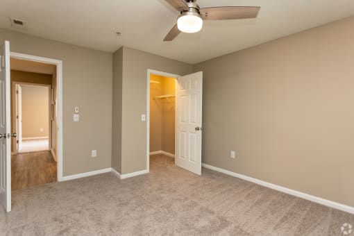 an empty living room with a ceiling fan and a door to a closet